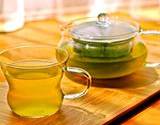 photo of a glass pot full of brewed green tea and a cup of green tea