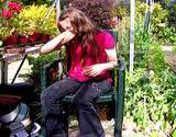 photo of a girl sitting in a greenhouse full of plants and suffering from hay fever