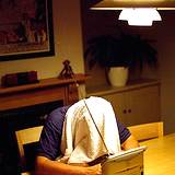 photo of a man holding his head over a hot steam bowl of water with towel over his head