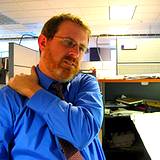 photo of man working in office rubbing shoulder for neck pain relief